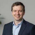 Профессиональный портрет уверенного российского бизнесмена с дружелюбным взглядом на размытом нейтральном фоне